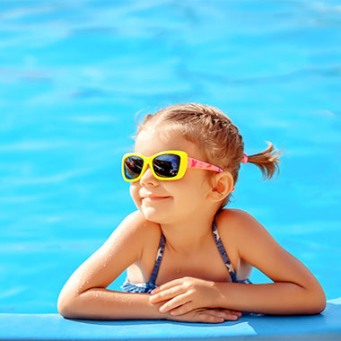 Małe dziecko uśmiecha się na brzegu basenu. Twardość wody w basenach może uszkodzić powierzchnie basenu i spowodować korozję rur.
